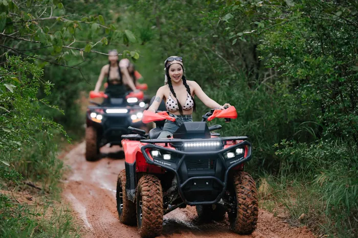 ลูกค้าสองคันขับ ATV ตามกันบนเส้นทางลูกรังที่ขนาบด้วยต้นไม้เขียว